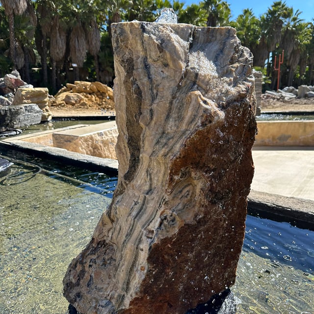 Black Canyon Onyx Cut Boulder Fountain displayed in a pond for sale at Southwest Boulder & Stone