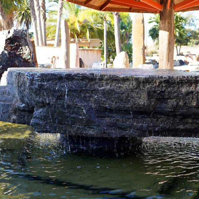 Carbon Frost Natural Boulder Fountain displayed in pond for sale at rock yard