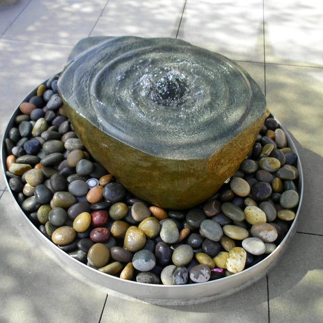 Basalt swirl stone fountain installed over mexican beach pebble 1