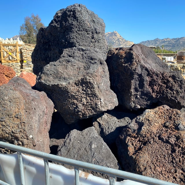 Black lava boulders in wire basket at rock yard